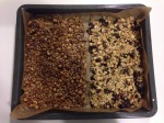 Ricetta Granola homemade al ciocoolato  e alla frutta secca e semi stendere il composto su una teglia con carta forno